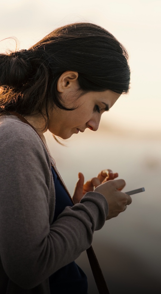 Junge Frau blickt angespannt auf ihr Handy