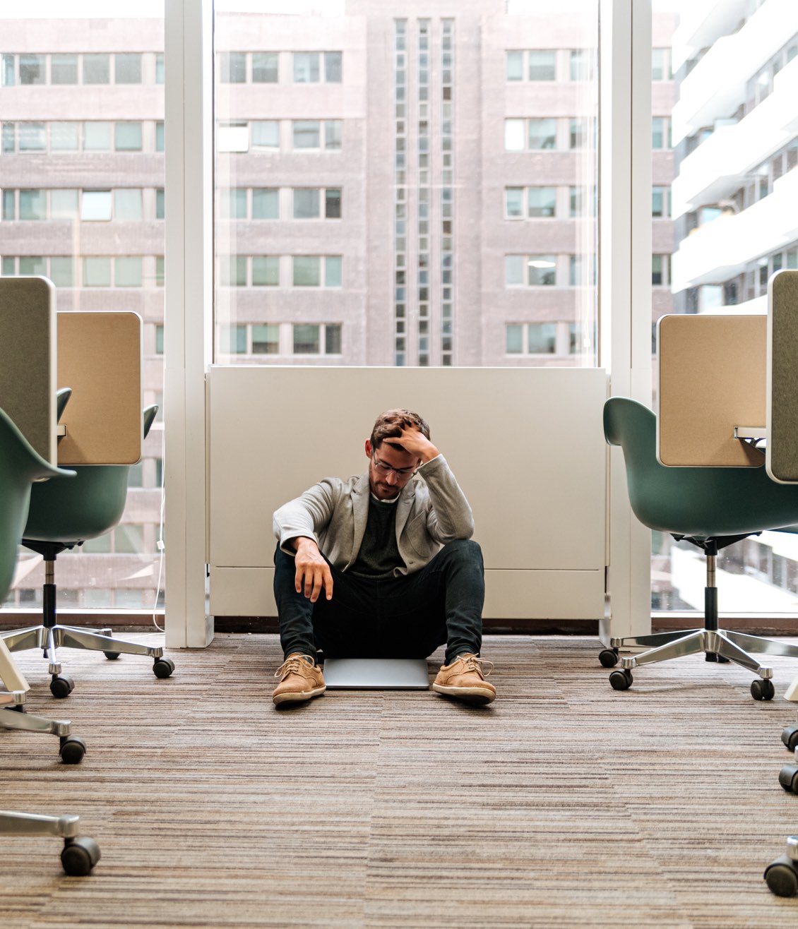 Mann mit Burn-out sitzt in seinem Office am Boden